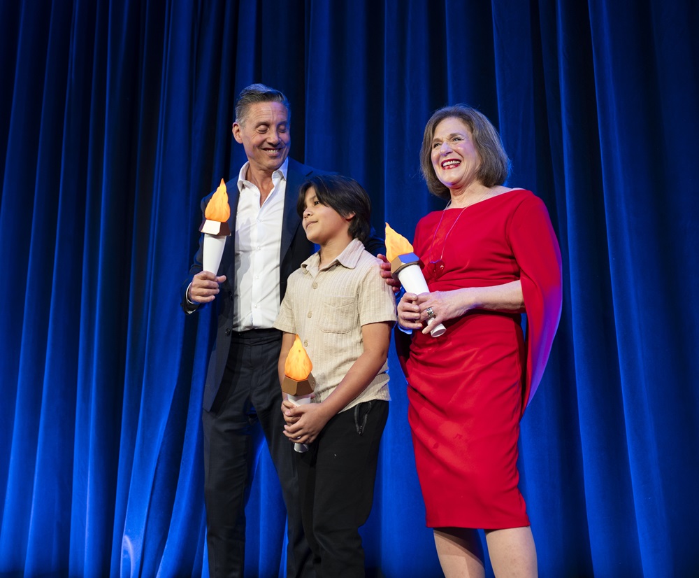 Man, woman, and child on stage holding mock torches.